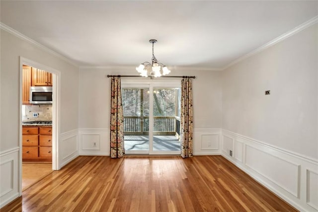 unfurnished dining area featuring hardwood / wood-style flooring, crown molding, and an inviting chandelier