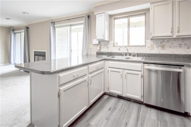 kitchen with a peninsula, a sink, ornamental molding, decorative backsplash, and dishwasher
