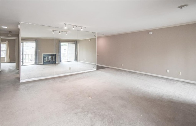 unfurnished living room with carpet, ornamental molding, and baseboards
