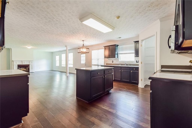 5900 Fairington Farms Ln, Stonecrest, GA 30038 - kitchen featuring a textured ceiling, dark wood-style floors, stove, a kitchen island, and a fireplace