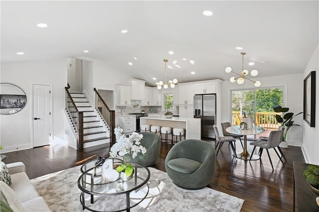 living room with vaulted ceiling, stairway, dark wood-style floors, and a notable chandelier