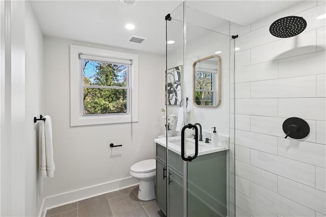 bathroom featuring toilet, vanity, tiled shower, baseboards, and tile patterned floors