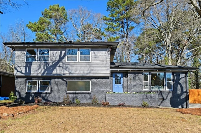 tri-level home with brick siding, a front yard, and fence