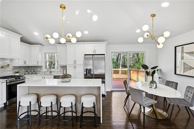 kitchen featuring a center island, a notable chandelier, vaulted ceiling, stainless steel appliances, and a sink