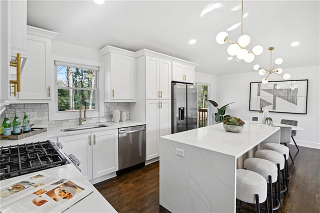 kitchen featuring appliances with stainless steel finishes, plenty of natural light, a sink, and a notable chandelier