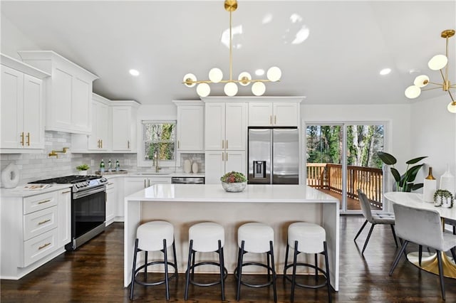 kitchen featuring stainless steel appliances, a sink, light countertops, and an inviting chandelier