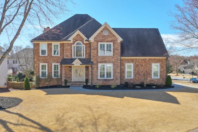 view of front of home with roof with shingles, a chimney, and a front yard