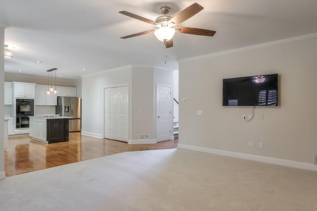 unfurnished living room featuring ornamental molding, a ceiling fan, visible vents, and baseboards