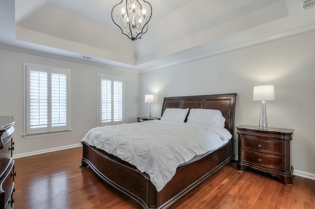 bedroom featuring dark wood-type flooring, a tray ceiling, and visible vents