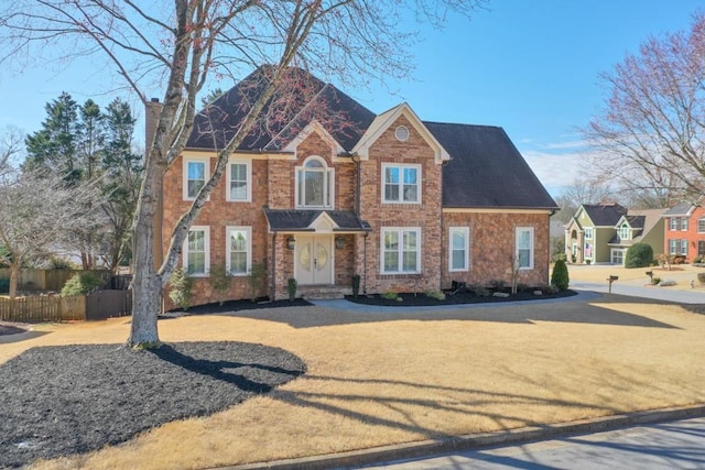 view of front of property featuring brick siding, fence, and a chimney