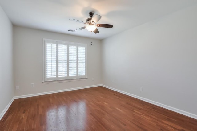 spare room with visible vents, dark wood finished floors, baseboards, and ceiling fan