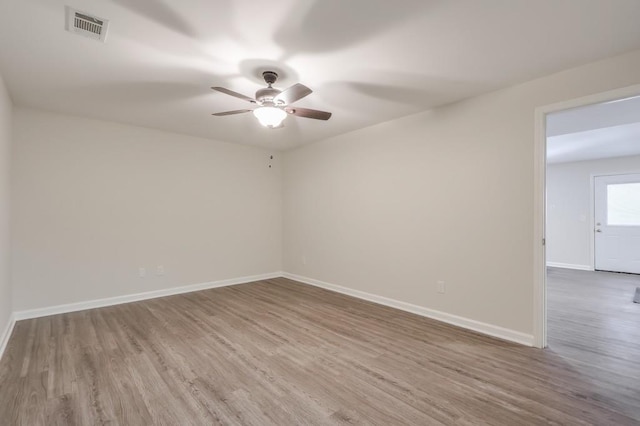 empty room with a ceiling fan, baseboards, visible vents, and wood finished floors