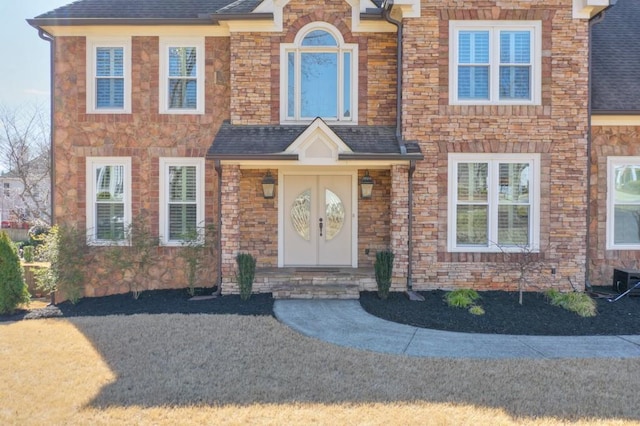 view of front facade with stone siding and a shingled roof