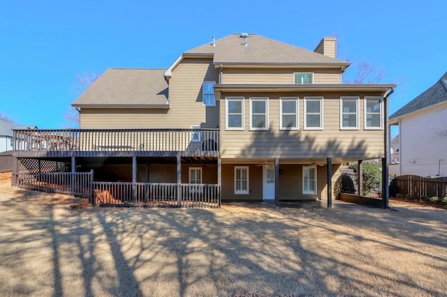 view of front facade featuring roof with shingles, a patio, a chimney, fence, and a wooden deck