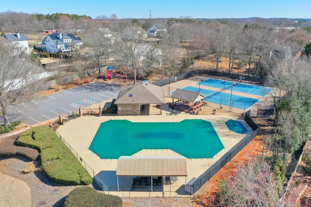 view of swimming pool featuring a tennis court and fence