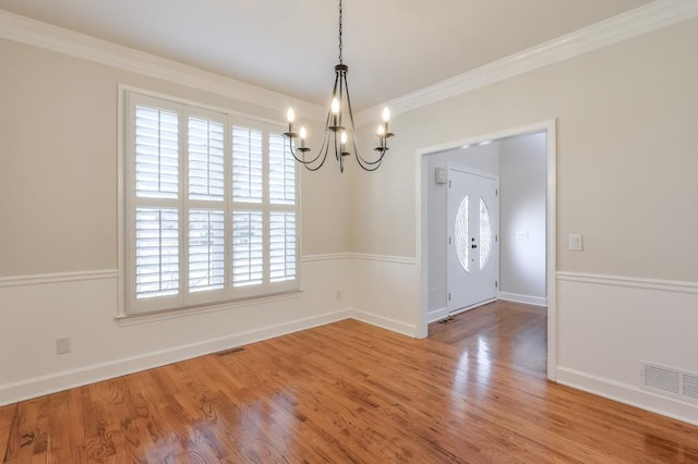 interior space featuring a chandelier, wood finished floors, visible vents, and crown molding