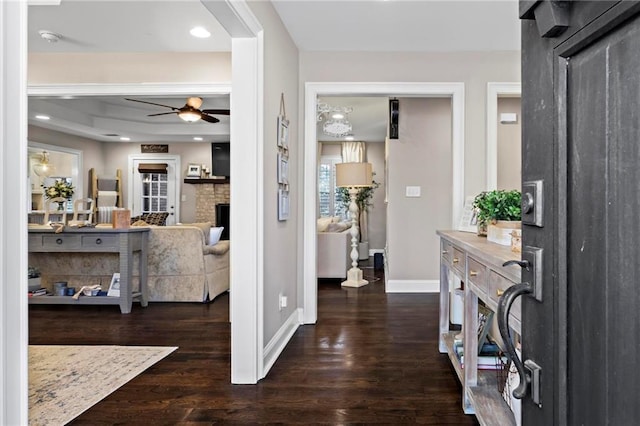 foyer entrance featuring ceiling fan, dark wood-type flooring, and a raised ceiling