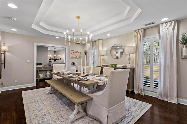 dining area featuring an inviting chandelier, dark hardwood / wood-style flooring, and a raised ceiling