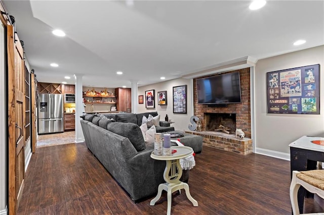 living room featuring a fireplace, a barn door, dark hardwood / wood-style floors, and bar area