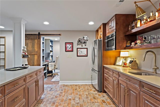 kitchen with a barn door, stainless steel fridge, and sink