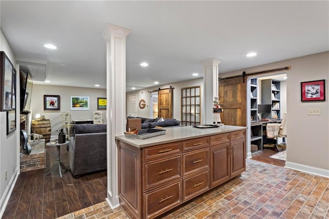 kitchen with a barn door, hardwood / wood-style floors, and decorative columns