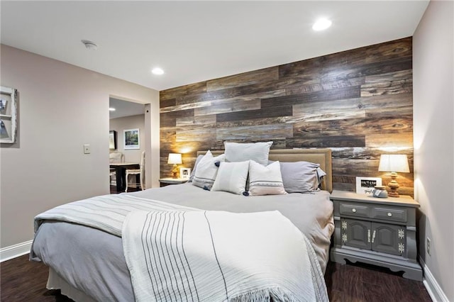 bedroom with dark hardwood / wood-style floors and wood walls