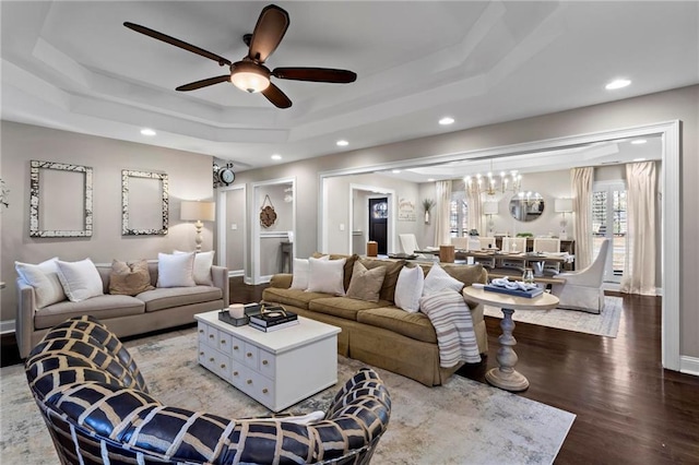 living room featuring ceiling fan with notable chandelier, hardwood / wood-style flooring, and a raised ceiling