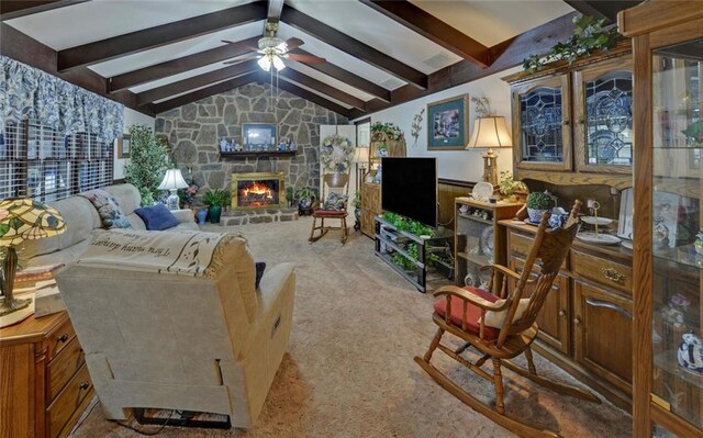 living area with a wainscoted wall, carpet floors, a ceiling fan, vaulted ceiling with beams, and a fireplace
