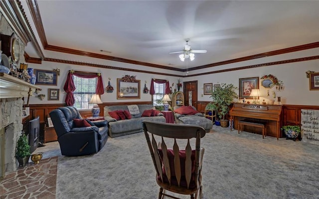 carpeted living room featuring a ceiling fan, a fireplace, wainscoting, visible vents, and ornamental molding