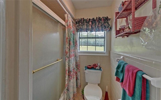 bathroom featuring a shower with shower curtain, toilet, and tile walls
