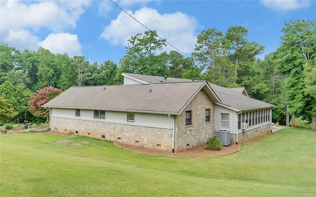 view of side of home featuring stone siding, roof with shingles, a lawn, a sunroom, and crawl space