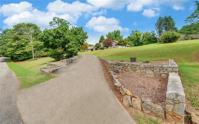 view of home's community with a lawn and aphalt driveway