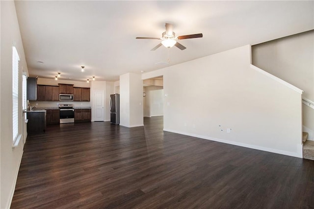 unfurnished living room with ceiling fan, dark wood-type flooring, and sink