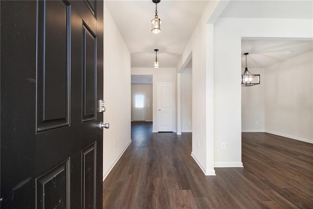 hallway with an inviting chandelier and dark hardwood / wood-style flooring