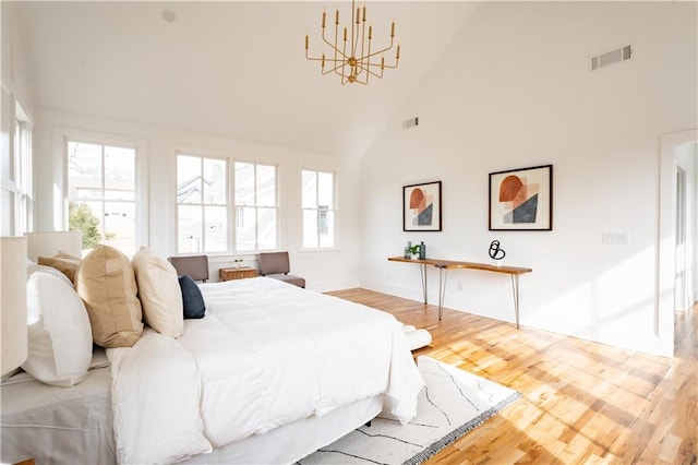 bedroom featuring an inviting chandelier, high vaulted ceiling, light hardwood / wood-style floors, and multiple windows