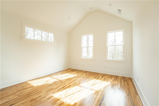 unfurnished room with lofted ceiling, wood-type flooring, and a wealth of natural light