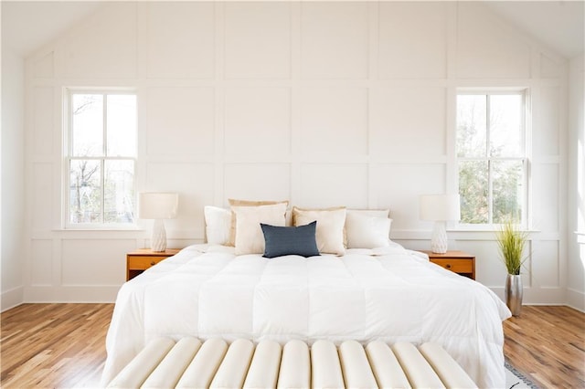 bedroom with multiple windows, vaulted ceiling, and light hardwood / wood-style flooring