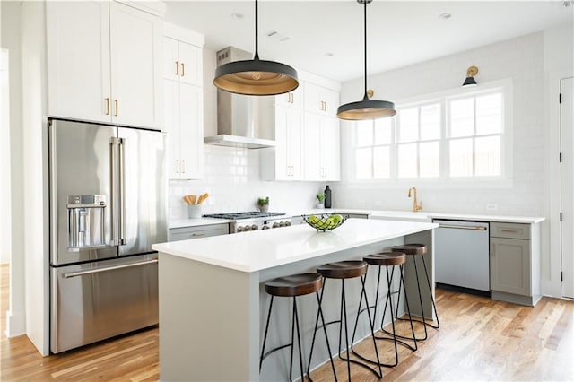 kitchen with a kitchen island, pendant lighting, a breakfast bar area, white cabinets, and stainless steel appliances