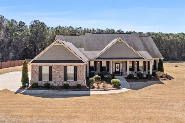 craftsman house with covered porch, a front lawn, and brick siding