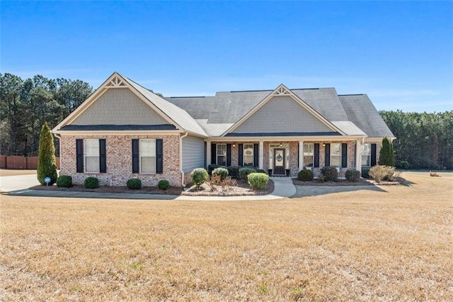 craftsman-style home featuring a porch, a front yard, and brick siding