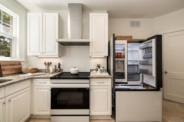 kitchen with visible vents, light stone counters, white electric range oven, white cabinetry, and wall chimney exhaust hood