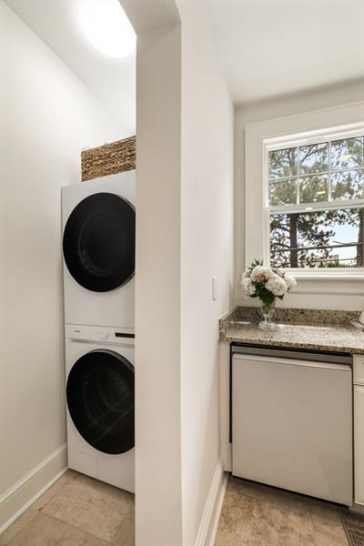 laundry area featuring laundry area, stacked washer / drying machine, and baseboards