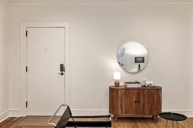 foyer entrance featuring wood finished floors, baseboards, and ornamental molding