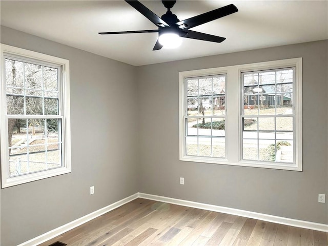 unfurnished room featuring a healthy amount of sunlight, baseboards, and wood finished floors