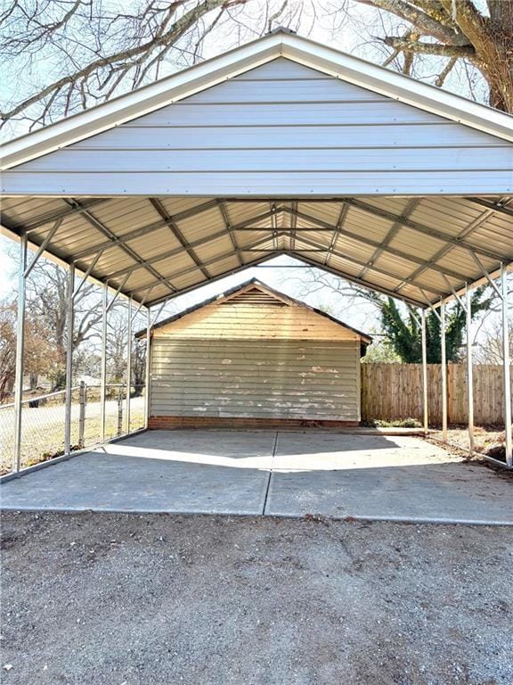 view of parking / parking lot featuring fence and a carport