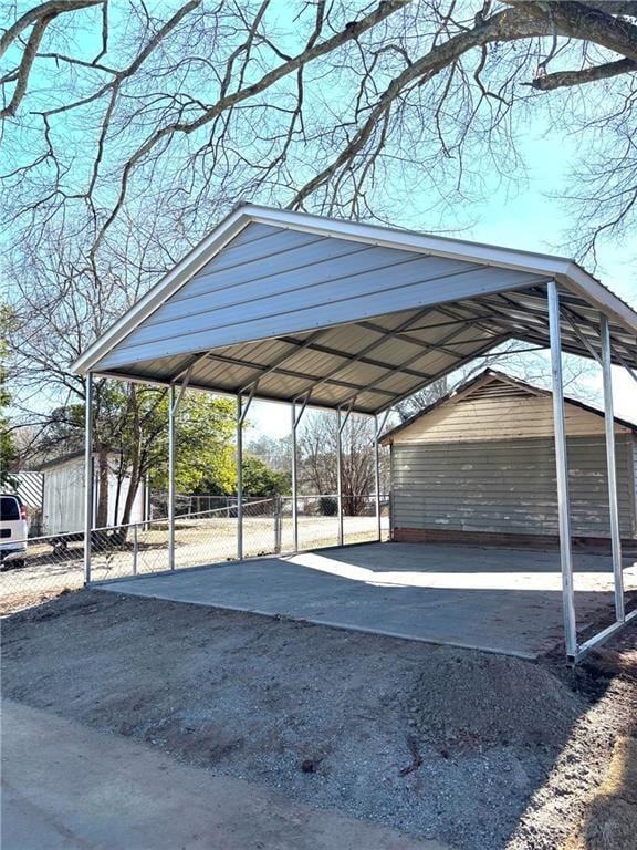 view of vehicle parking featuring fence and a detached carport