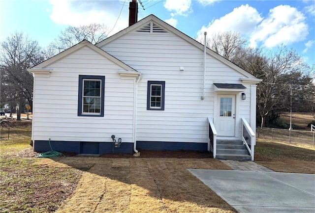 rear view of house with entry steps and a chimney