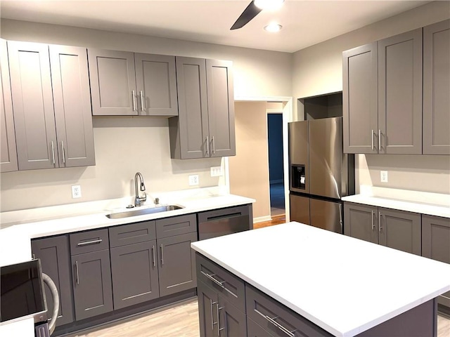 kitchen featuring stainless steel appliances, light countertops, a sink, and gray cabinetry