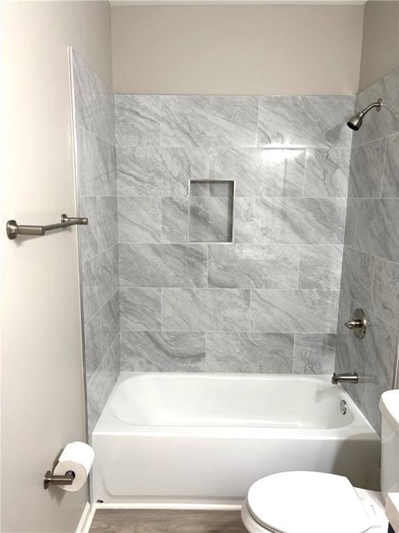 bathroom featuring toilet, tub / shower combination, and wood finished floors