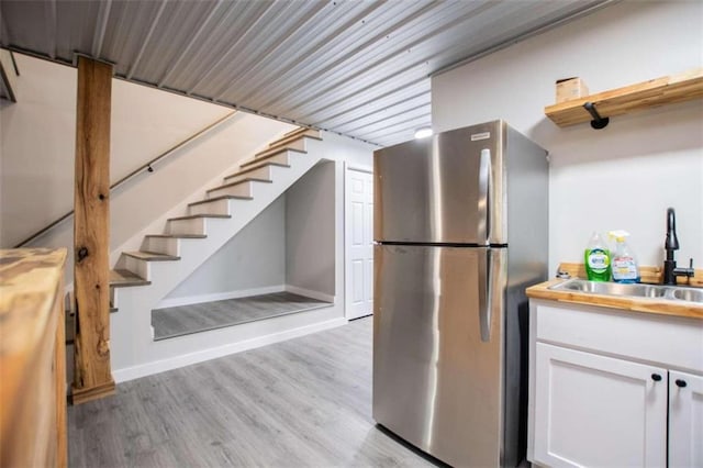 2125 Mccollum Church Rd, Lineville, AL 36266 - kitchen with freestanding refrigerator, a sink, light wood-style flooring, white cabinetry, and baseboards